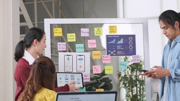 亚洲用户体验开发人员和ui设计师在现代办公室会议的白板上展示和测试手机应用界面设计创意数字开发移动应用机构