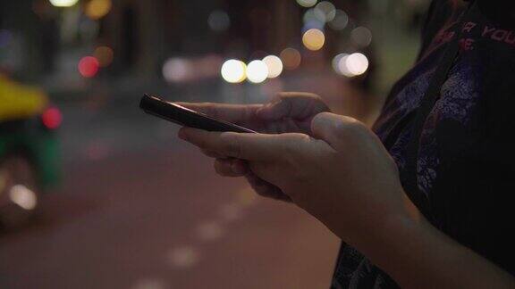 亚洲女性用智能手机在路边叫出租车
