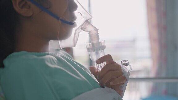 一个亚洲女孩在医院戴着氧气面罩用喷雾器呼吸