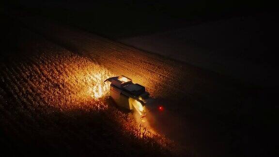 无人机拍摄的联合收割机使用车头灯在夜间切割玉米作物