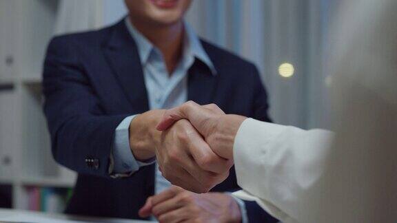 年轻的亚洲商人在办公室签订合同、投资专业文件、协议和握手的特写职场上的商务人士