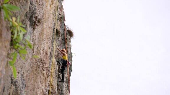 4K亚洲成熟女子攀登岩石山悬崖在热带岛屿