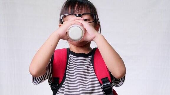 可爱的女生在上学前用杯子喝牛奶儿童健康营养回到学校概念