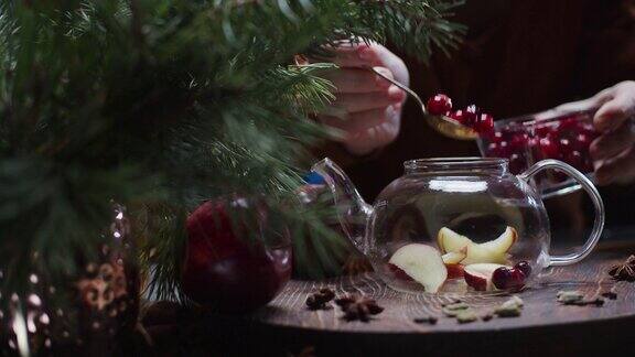 人们正在用手准备用苹果和蔓越莓制作的圣诞风味茶