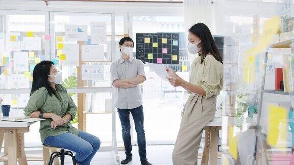 亚洲商务人士在新常态的办公室里开会头脑风暴进行商业演示想法项目同事并戴上防护口罩