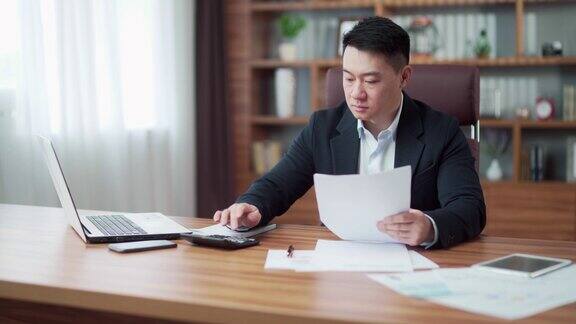 专注的亚洲商人签署合同审查财务文件或报告在工作场所处理文件的商人