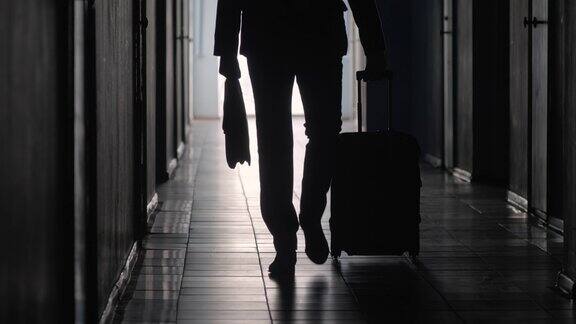 剪影的商务旅行者走在走廊上与行李