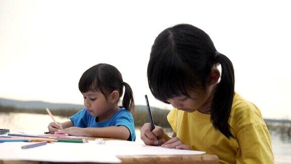 兄弟姐妹用彩色铅笔在纸上画漫画的场景教育背景股票