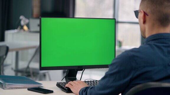年轻人在办公室用绿色的模拟屏幕工作