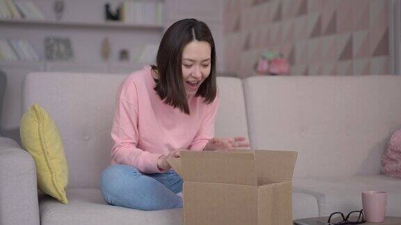 年轻的亚洲女性客户在家里打开纸箱满意的消费者打开包裹