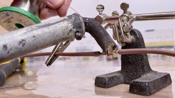 一个工匠的手焊接两根电线的极端特写车间的焊接过程