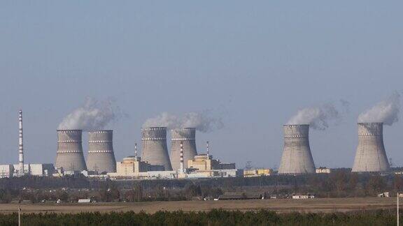 核电站的景象蓝天下核电站冒烟的烟囱、电线和森林