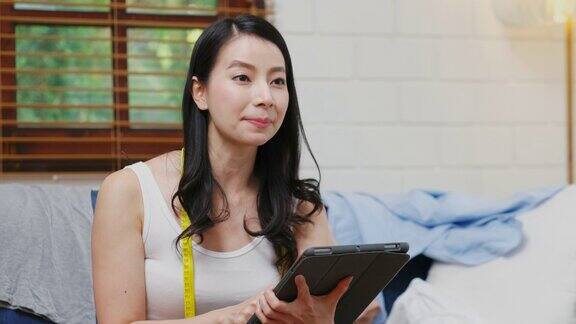 年轻的亚洲女性时尚博主博主手持数字平板电脑与客户交谈同时直播网上购物商业和技术
