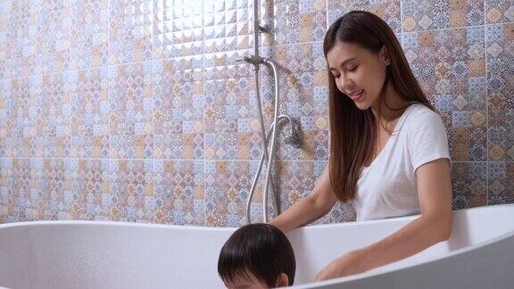 妈妈在浴室的浴缸里给可爱的小儿子洗澡