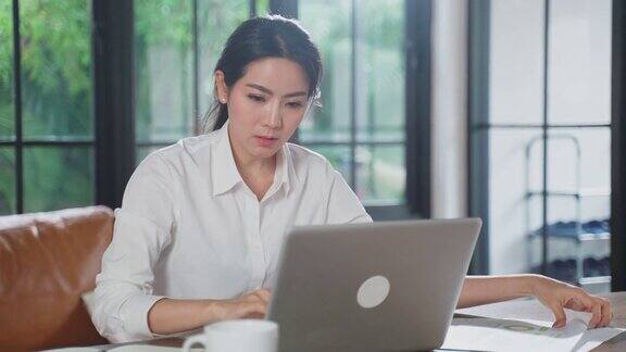 亚洲女商人在家用电脑工作的肖像女人坐在桌子上感到无聊和不开心由于新冠肺炎大流行压力山大的女孩对在家工作感到失望