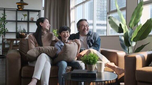 幸福的亚洲家庭一起在客厅的沙发上看电视家庭家居概念