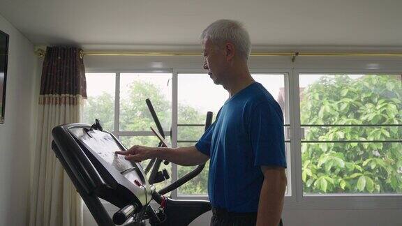 亚洲中年男子在跑步机上跑步在家锻炼身体保持身体健康