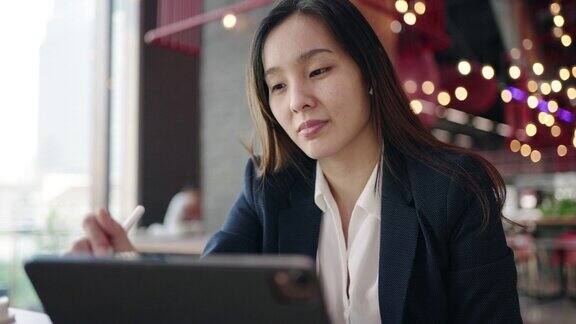 亚洲女商人在咖啡馆使用数字平板电脑