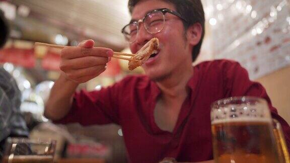 亚洲男子享受居酒屋日本餐厅