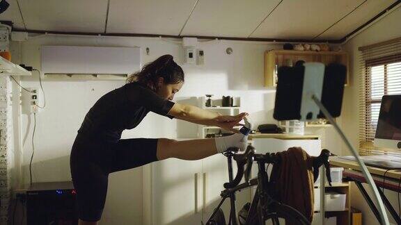 亚洲女性自行车手她正在家里锻炼她骑着模拟自行车她伸展