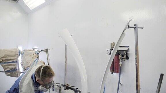 男工人正在喷漆室粉刷金属细部手工作业