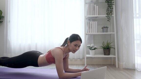 美丽的亚洲年轻女子学习瑜伽在线视频会议健身教练在线瑜伽视频电话在笔记本电脑上