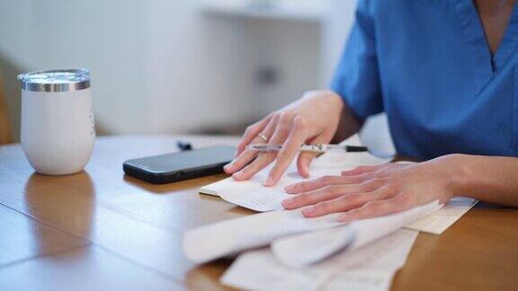 年轻的日本成年护士坐在家里的客厅里写下她的财务账单