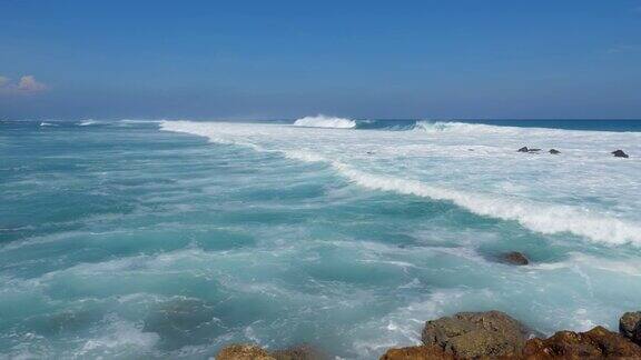 远处海浪拍打白色的水向岸边流去广角镜头