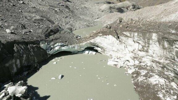 无人机俯瞰冰柱之间的寒冷池塘周围是粗糙的岩石山景观