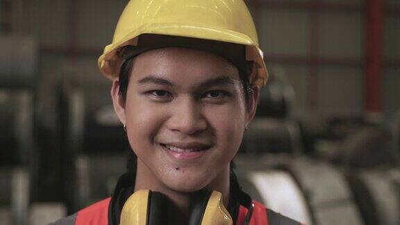 肖像快乐的职业亚洲人工人戴着黄色安全安全帽站在微笑看着相机在工厂