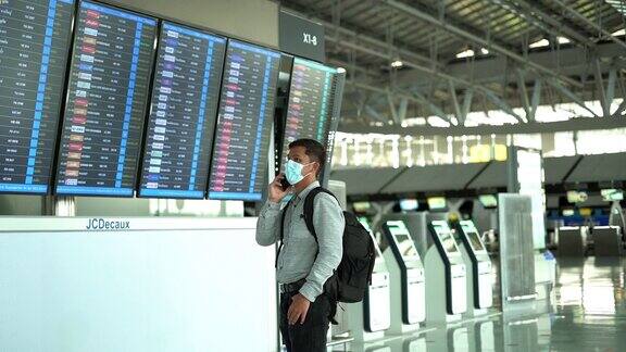 日落时分一名亚洲男子走进候机楼在机场门口查看航班时刻表