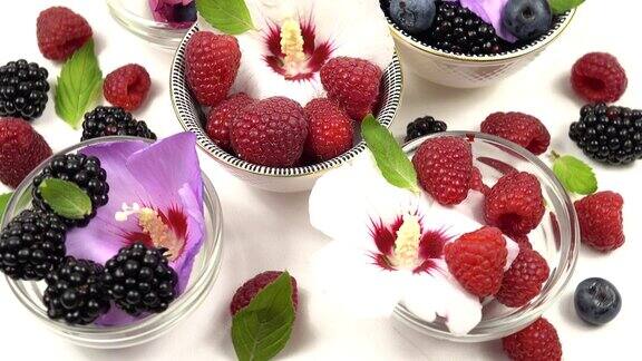白色桌子上的小碗里放着锦葵树、覆盆子、黑莓和蓝莓的花