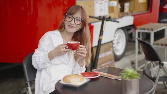 在快餐车咖啡馆里一名亚洲女子一边喝着咖啡一边看着别人微笑