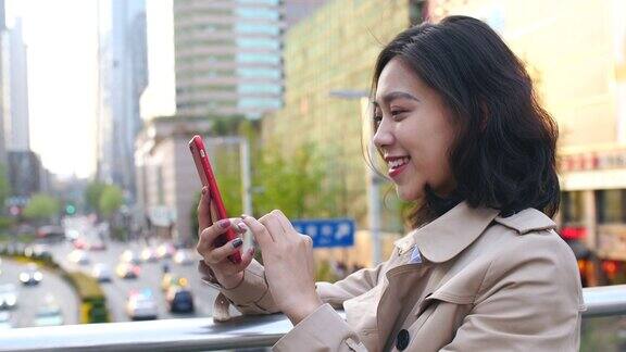 下午在中国城市成都的立交桥上一名非常快乐的年轻亚洲女子在用手机背景是繁忙的道路