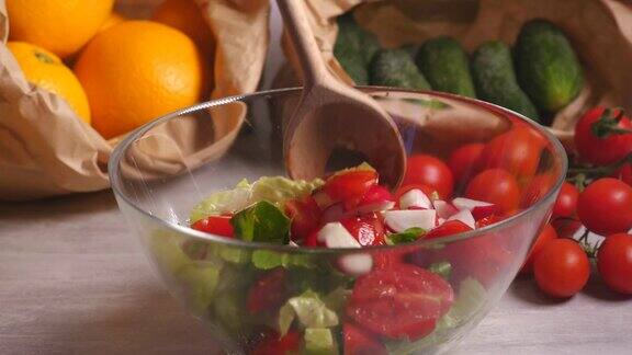 用铲子混合西红柿、黄瓜、生菜和萝卜做成的蔬菜沙拉
