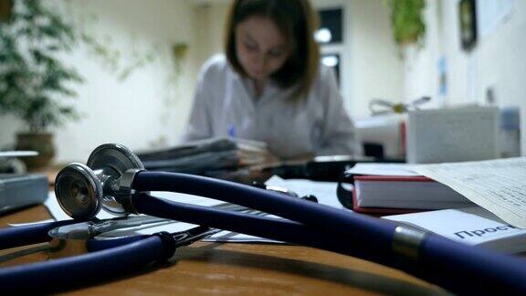 年轻护士在办公桌旁写病历女医生在医院开处方听诊器上的前景卫生保健近距离