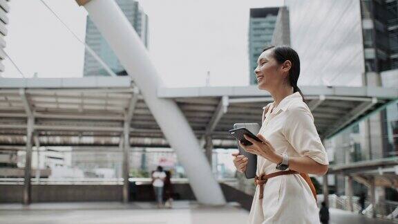 亚洲女性在城市户外行走时用智能手机看屏幕