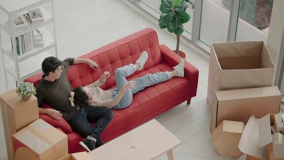 快乐的年轻亚洲夫妇把新沙发搬到客厅