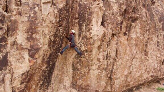 男子运动员爬上高高的岩石