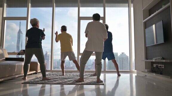 亚洲中国资深男子教他的资深朋友太极享受家庭锻炼在晚上在公寓客厅