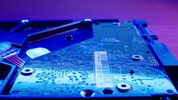 用蓝灯照亮的模糊背景上的硬盘驱动器芯片机构特写