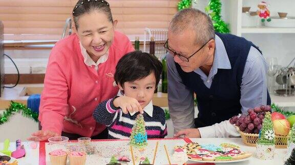 亚洲祖父母和小男孩在做饼干和面包店在圣诞节