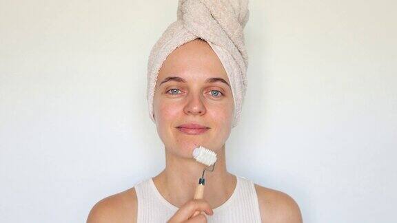 漂亮的女人使用化妆滚轮按摩脸部用化妆工具护理她的美脸流行的化妆项目孤立在白色背景上
