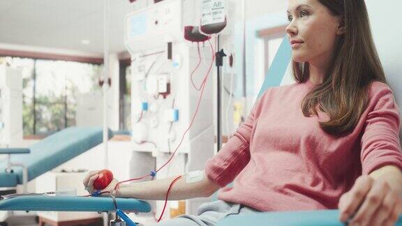 白人妇女在医院为有需要的人献血女性献血者挤压心形球将血液通过管道泵入袋中为怀孕期间有并发症的妇女捐赠