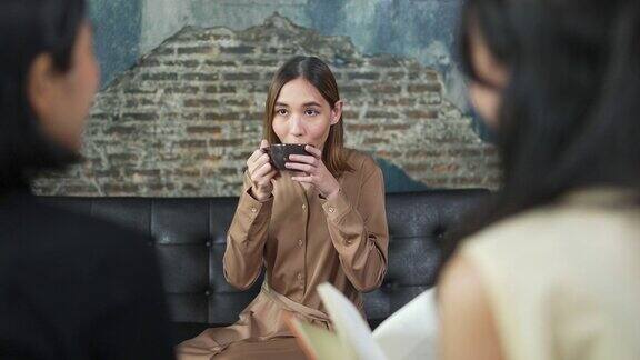 一群亚洲女性朋友坐在沙发上聊天一起在咖啡馆喝咖啡