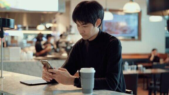 年轻的潮男在咖啡店用手机