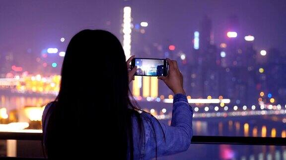 年轻女子在城市的夜晚拍照