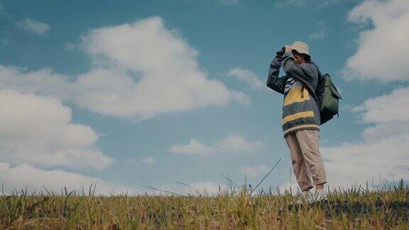 一个女徒步旅行者用双筒望远镜看东西的照片