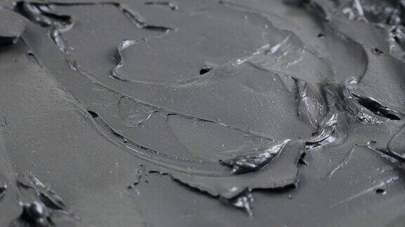 黑色粘土和泥面膜光滑的奶油质地涂抹圈旋转接近