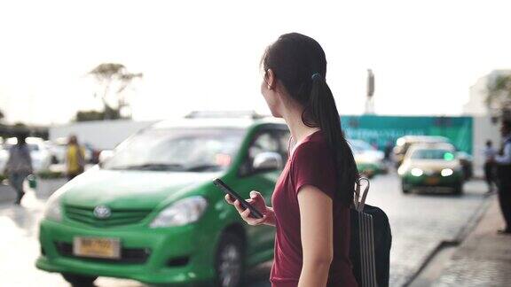 亚洲女性使用智能手机请求和等待出租车